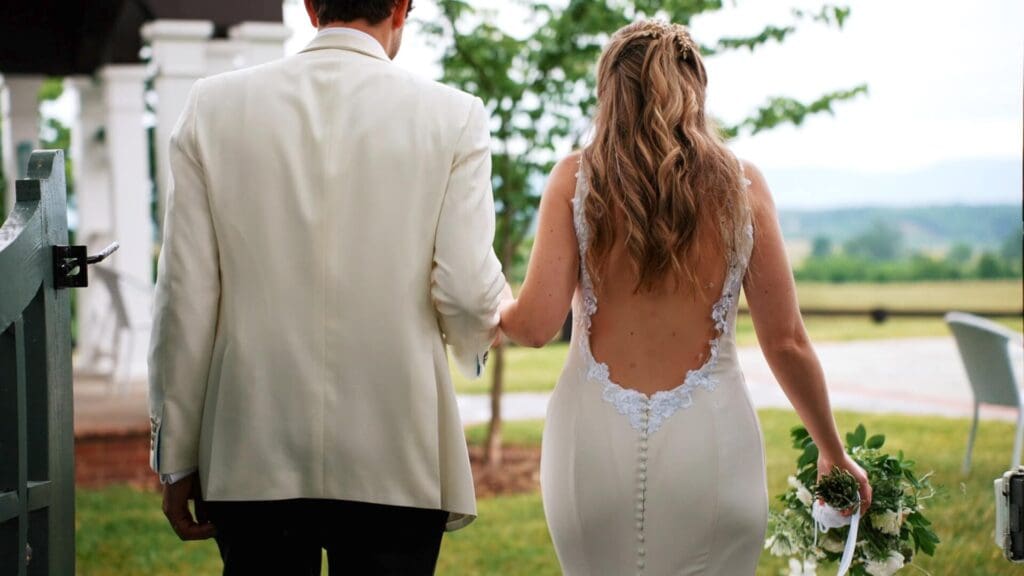 Bride and groom from behind, holding hands.